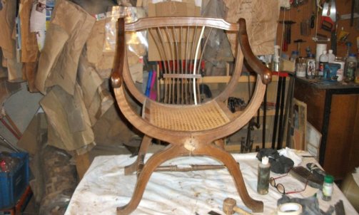 Ce petit fauteuil canné en X sera démonté et recollé.Un brin de la gerbe de blé cassé sera refait avant les finitions.                                  Restaurateur de meubles à Lavaur.